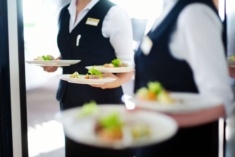 Waiter carrying platters of food during an event. (Photo by MNStudio via Getty)