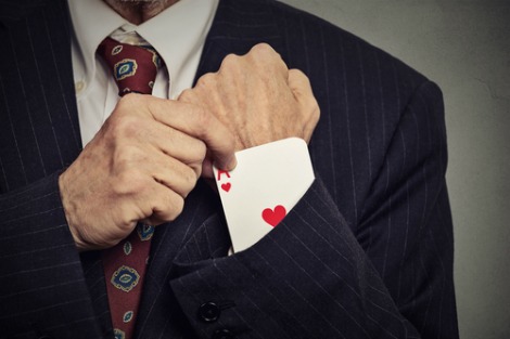 Man in suit pulls ace of hearts out of sleeve