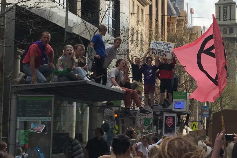 Protestors lead chants from the summit of a tram stop shelter on Bourke Street in Melbourne during the Strike 4 Climate rally on 20 September 2019. (Credit: Tim Kroenert)