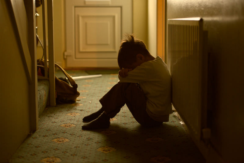 Boy sitting with his head down in a hallway (Getty Images/fiorigianluigi)
