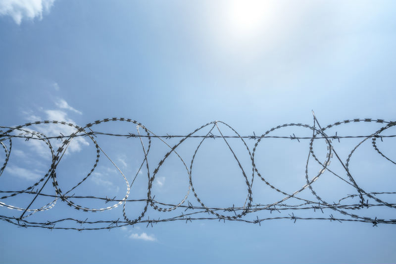 Barbed wire fence against blue sky (Getty images/Xinzheng)
