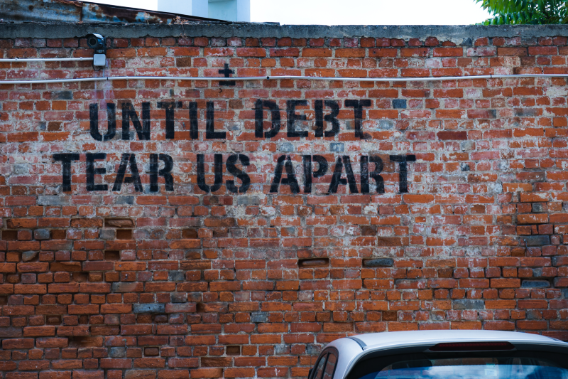 Main image: wall reading 'until debt tear us apart' (Ehud Neuhaus/Unsplash)
