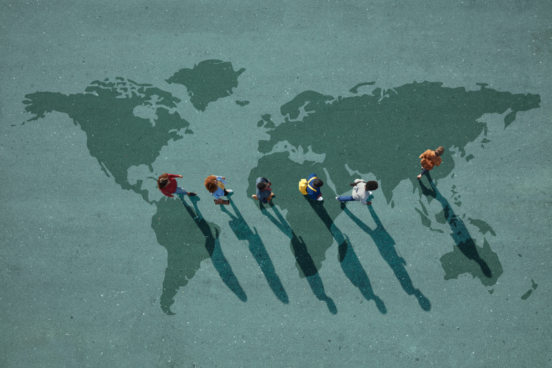People walking across world map (Klaus Vedfelt/Getty Images)