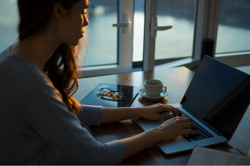 Woman on computer sitting at home (Thought Catalog/Unsplash)