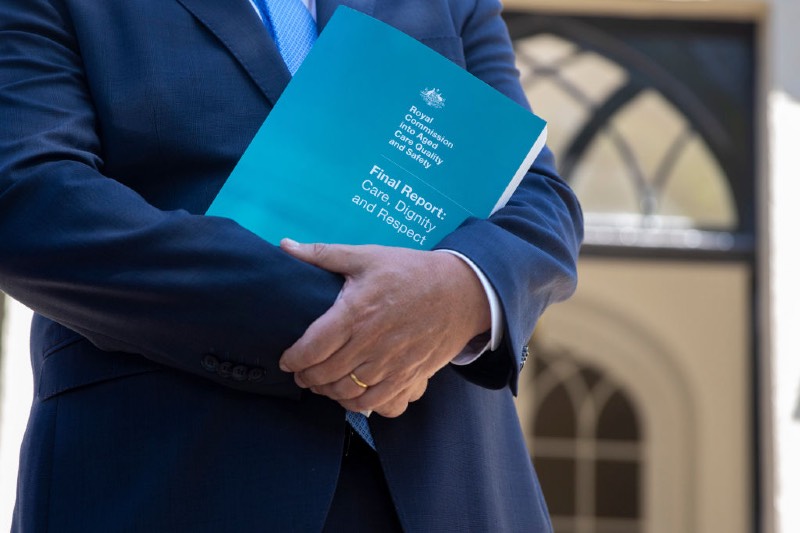 Main image: A close up is seen of the cover of the Australian Royal Commission Report into Aged Care during a press conference at Kirribilli House (Jenny Evans/Getty Images)