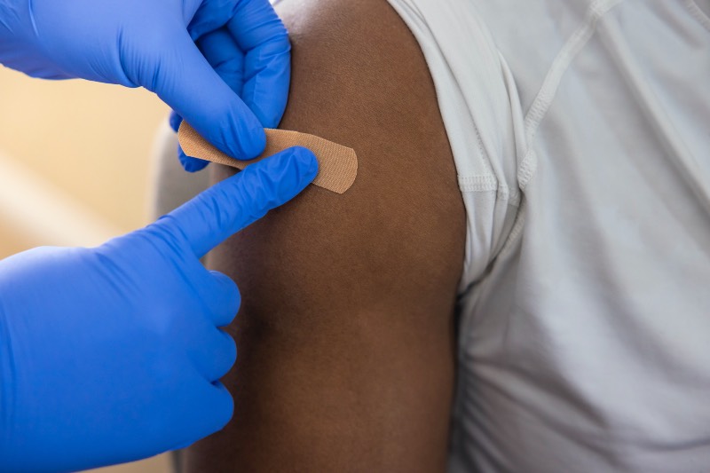 Main image: Close up of doctor putting bandaid on someone's arm after vaccination (Getty)