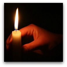 Hand holds candle in dark