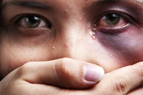 Woman with black eye weeps as a male hand covers her mouth